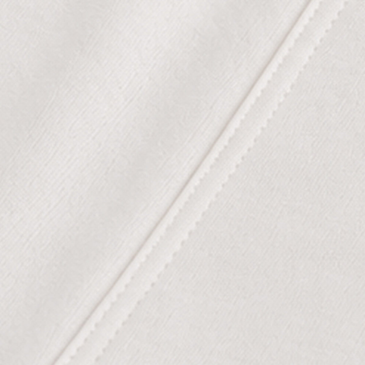 Close-up of a white textured fabric with a diagonal stitched seam.
