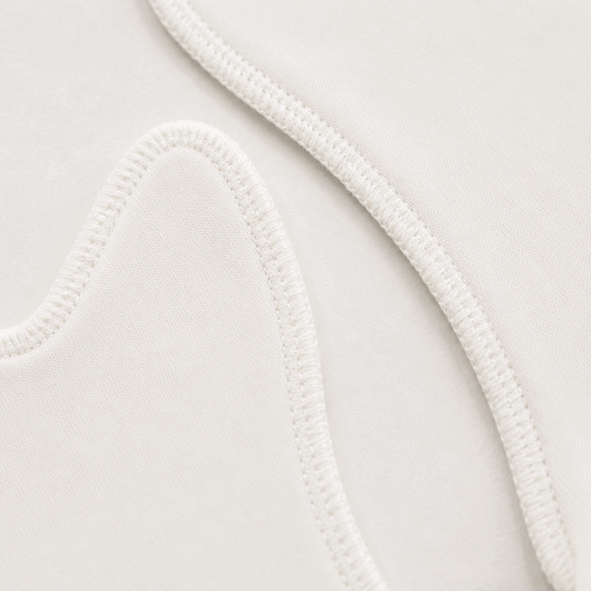 Close-up of a white or off-white fabric surface with a curved overlocked seam