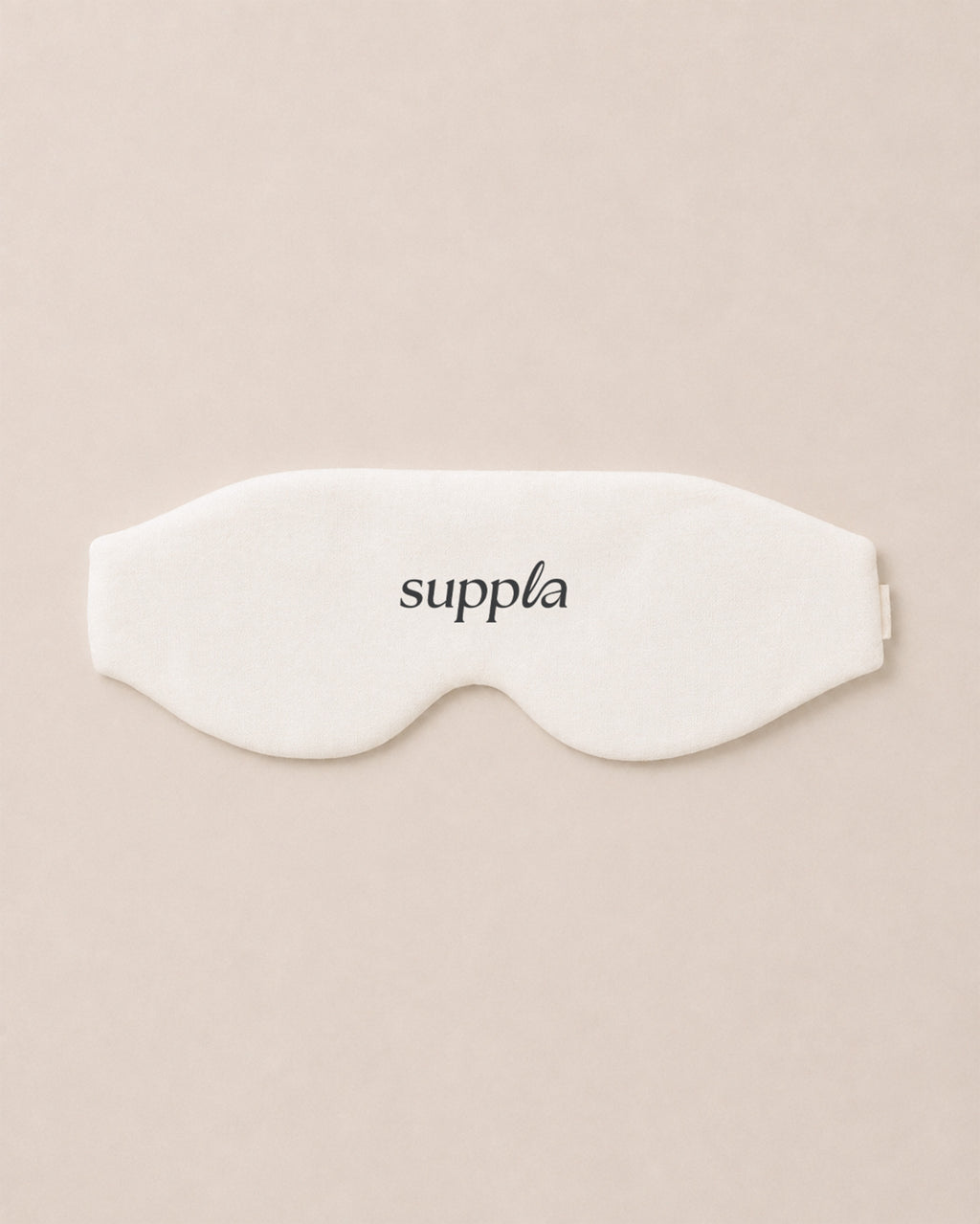 A white sleep mask with the brand name 'suppla' printed in black lowercase letters, centered on a solid beige background.