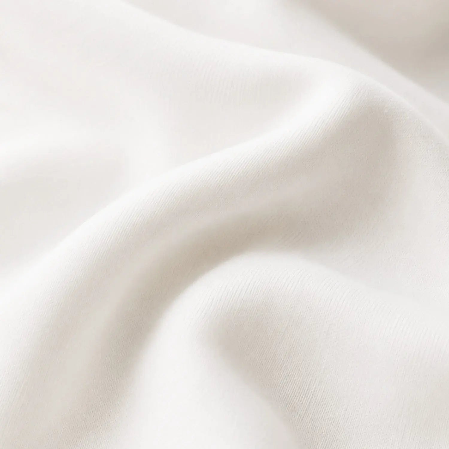 A close-up of softly draped off-white fabric with gentle folds and a smooth texture.
