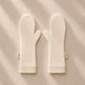 A pair of suppla scratch mittens with ribbed cuffs, laid flat on a  background with soft diagonal shadows. Small fabric tags on the wrists read 'suppla'