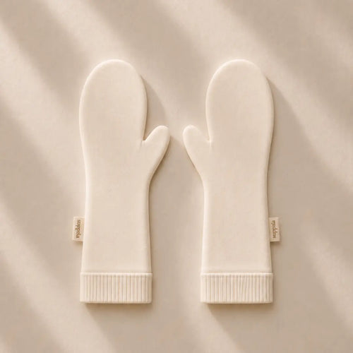 A pair of suppla scratch mittens with ribbed cuffs, laid flat on a  background with soft diagonal shadows. Small fabric tags on the wrists read 'suppla'